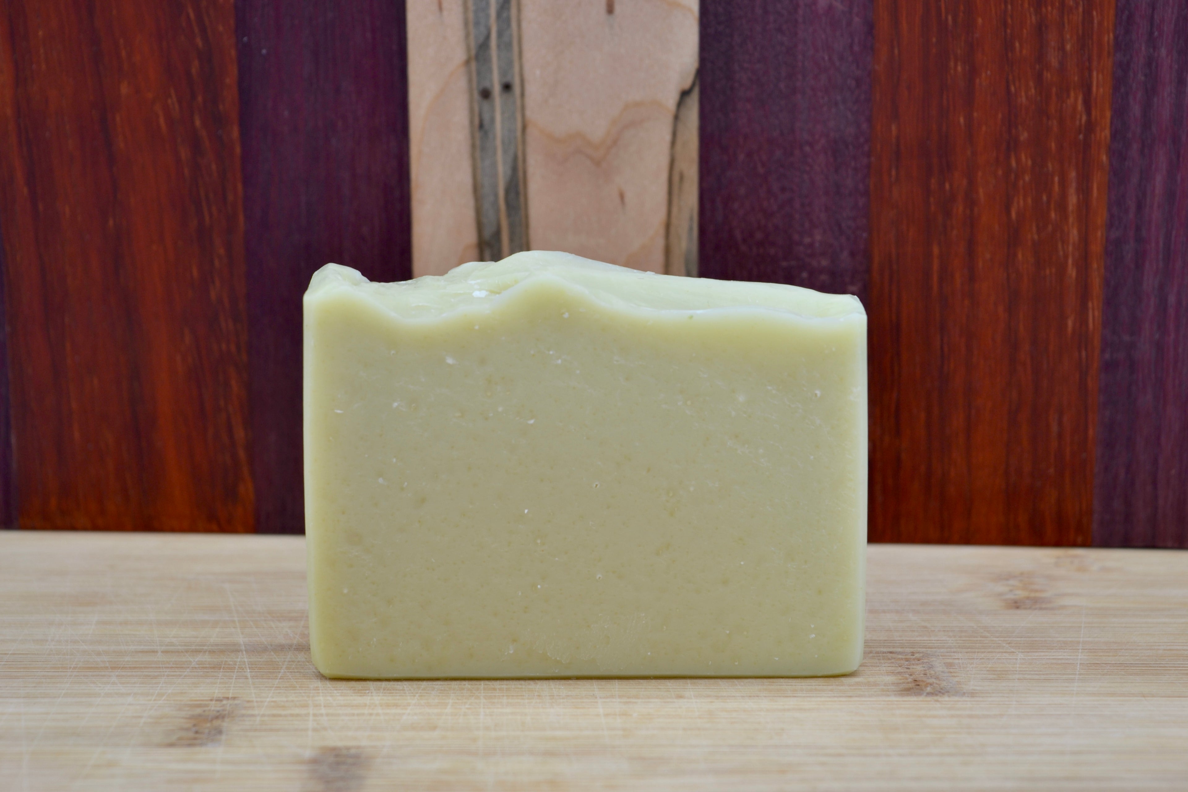 Light Green bar of soap on a wooden surface with a wooden background