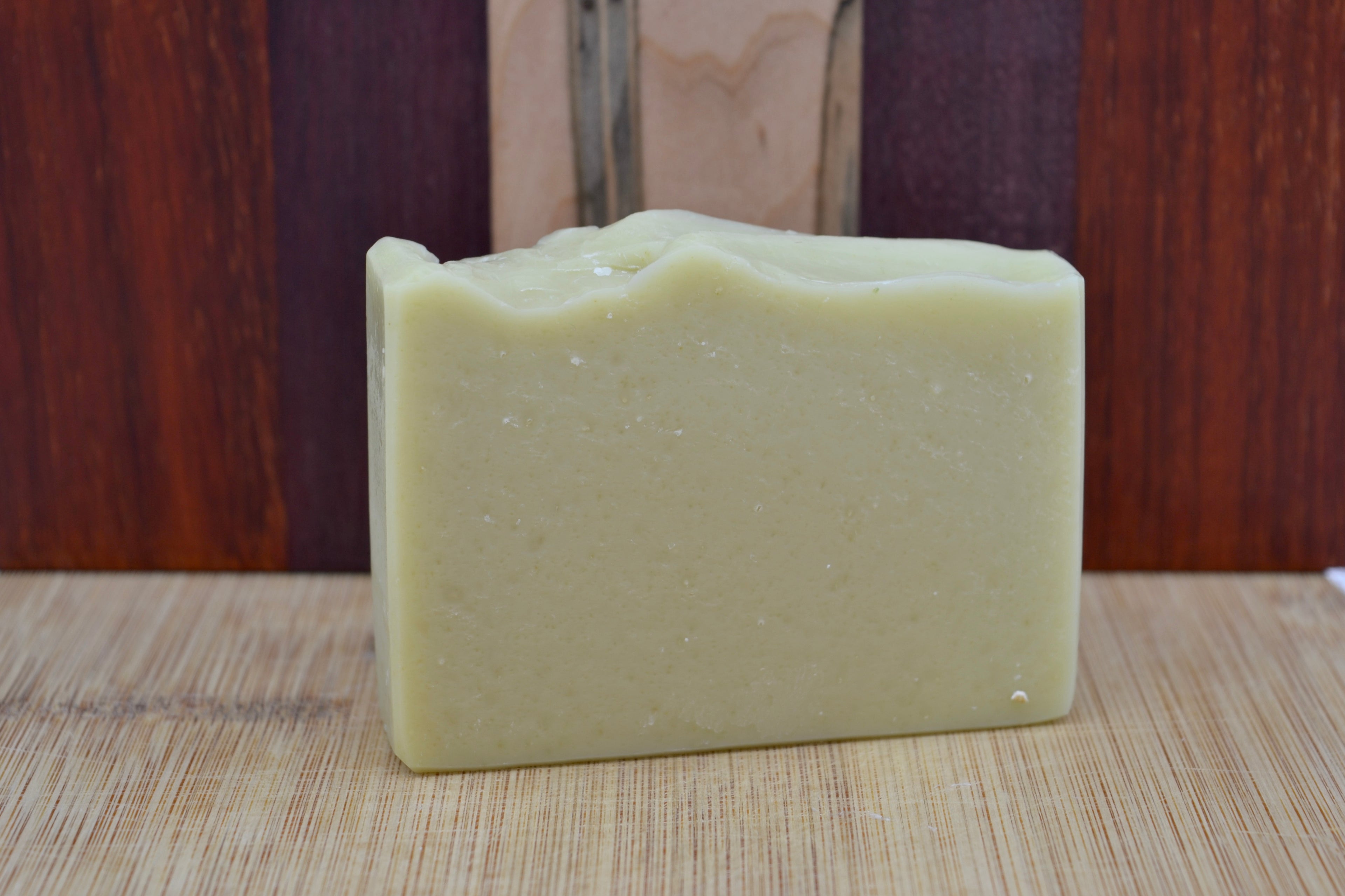Light Green soap bar with purple and dark walnut wood background 