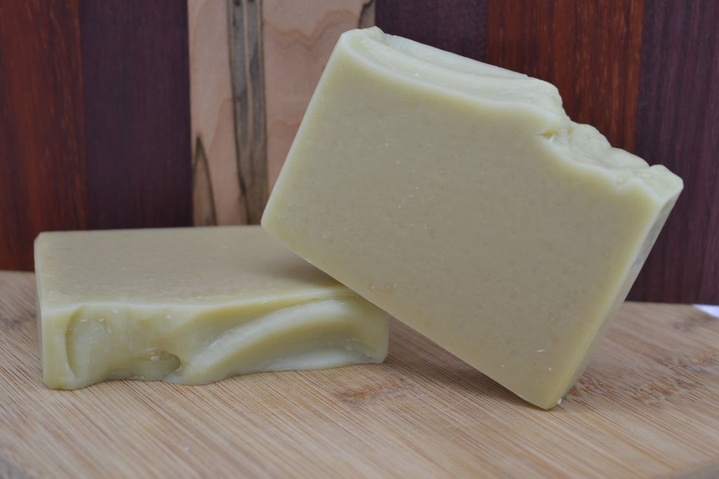 Two bars of soap on a wooden surface with a wooden background 