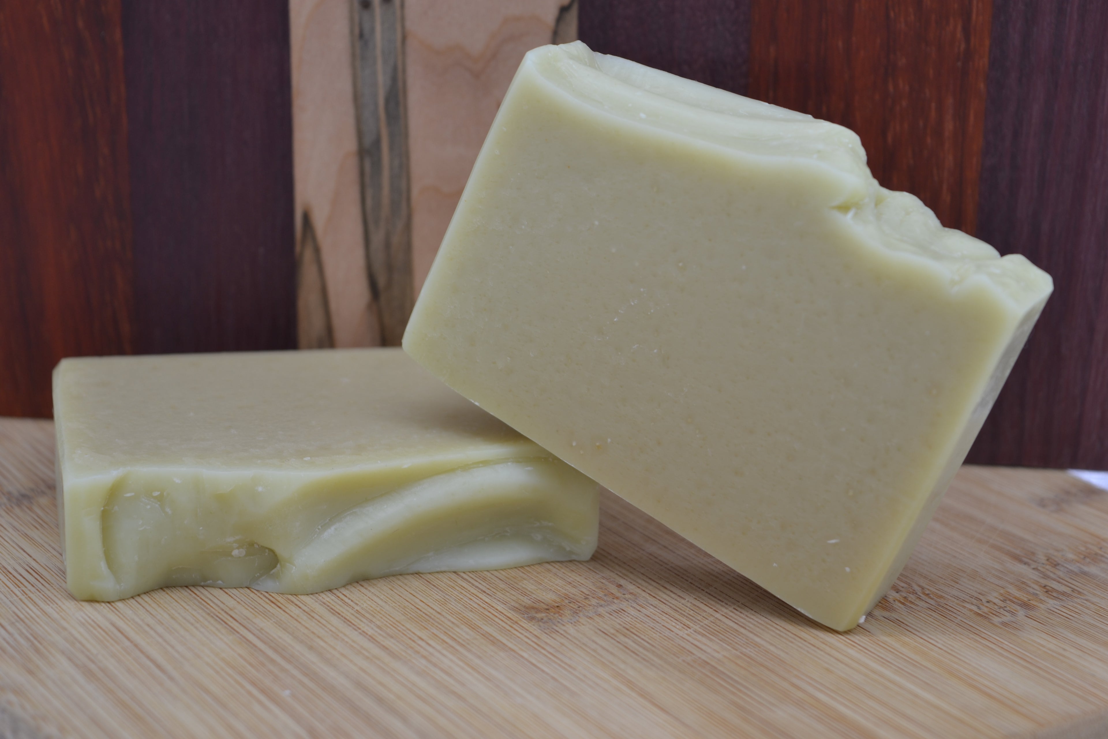 Two bars of soap on a wooden surface with a wooden background 