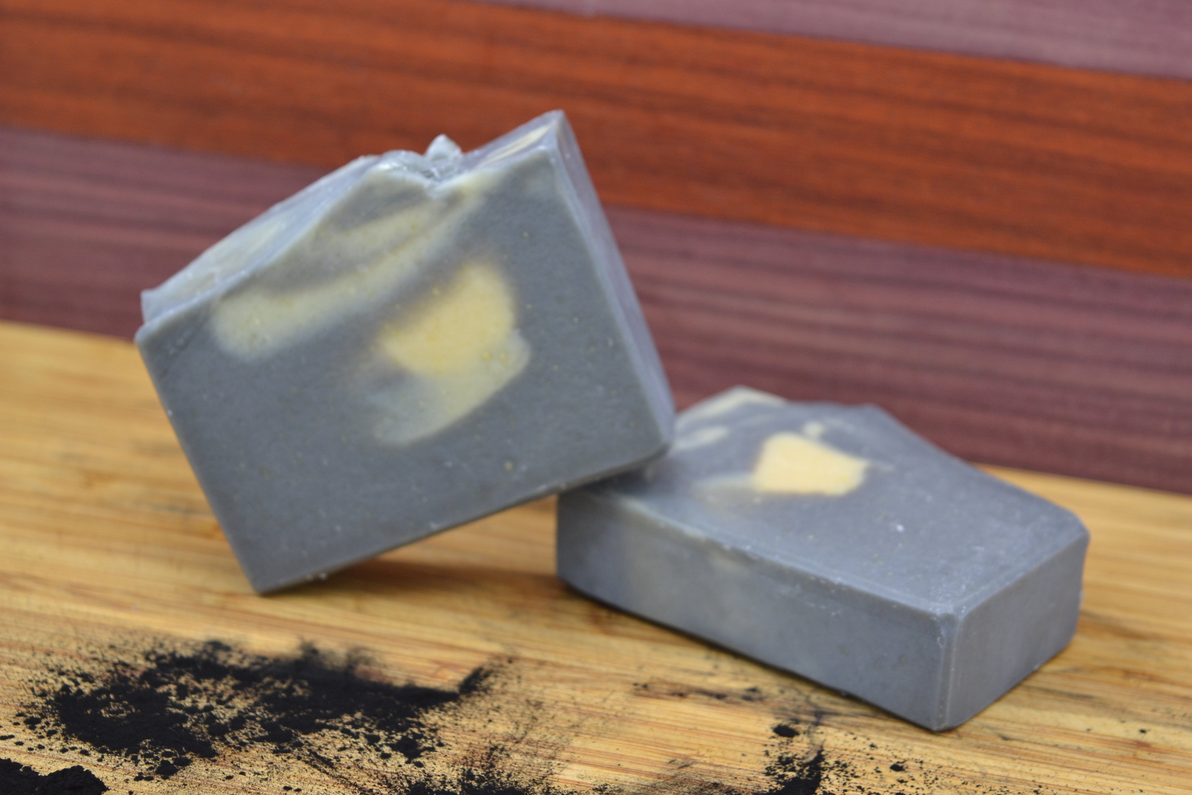 Two gray soap bars with white swirls on a wooden surface.